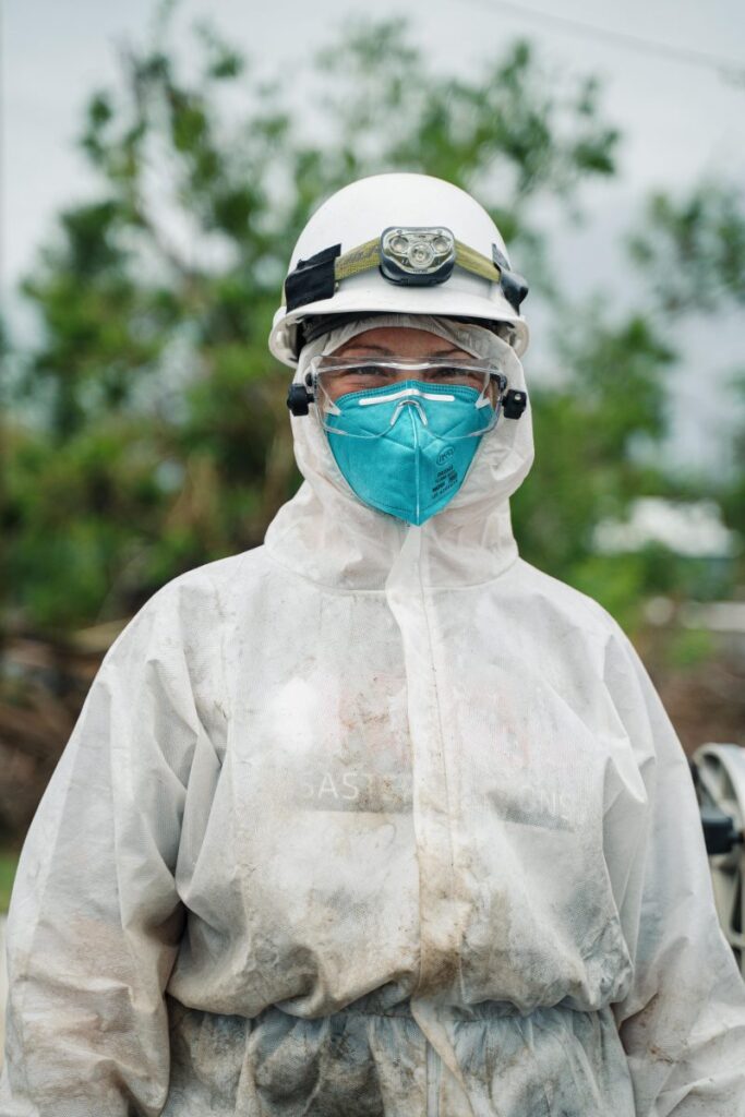 A volunteer wearing proper PPE asn they clean up after a flood