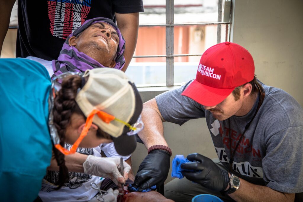 Two people provide medical aid to a grimacing Filipino woman. 