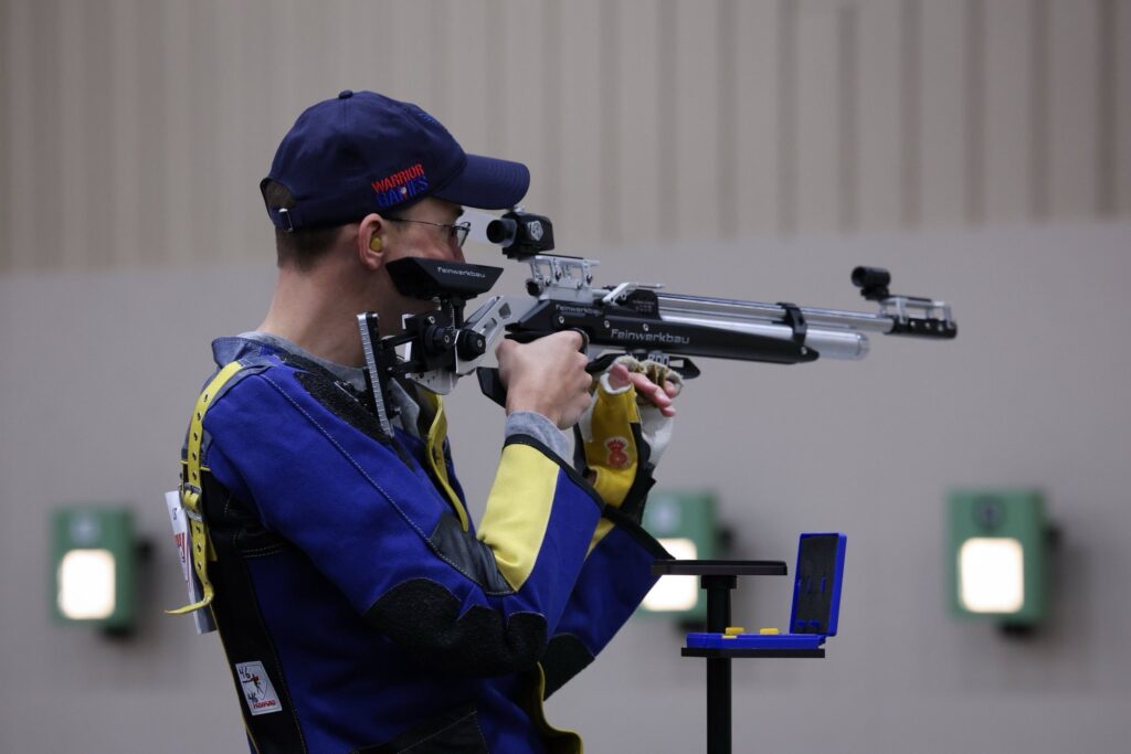 man aiming standing rifle 